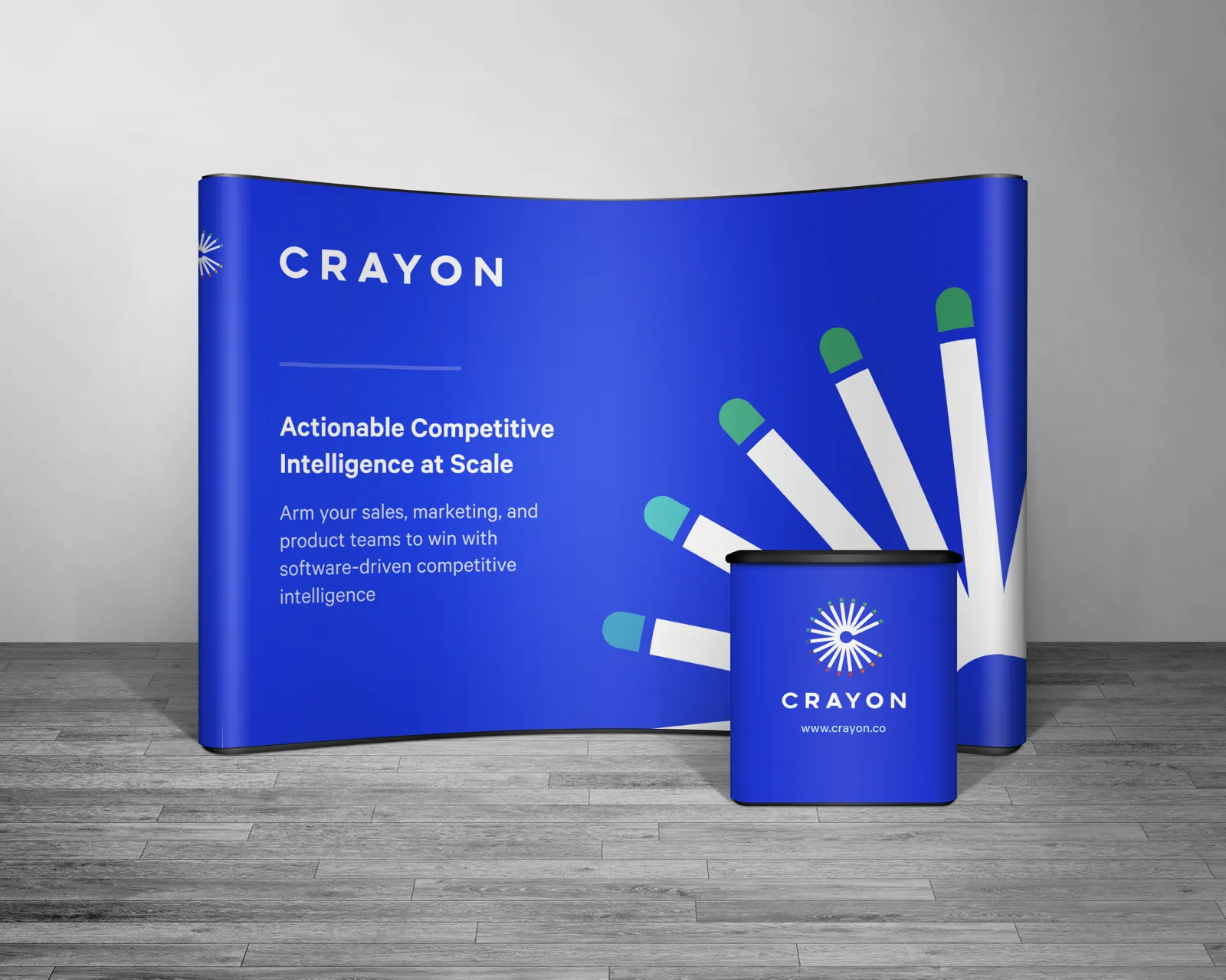 Trade show booth graphic in blue with a fan of crayons and the headline Actionable Competitive Intelligence at Scale